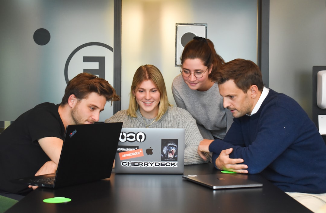 Four colleagues reviewing figures together around a laptop in a modern office, representing the credit committee review that an AI-drafted credit memo must support rather than replace