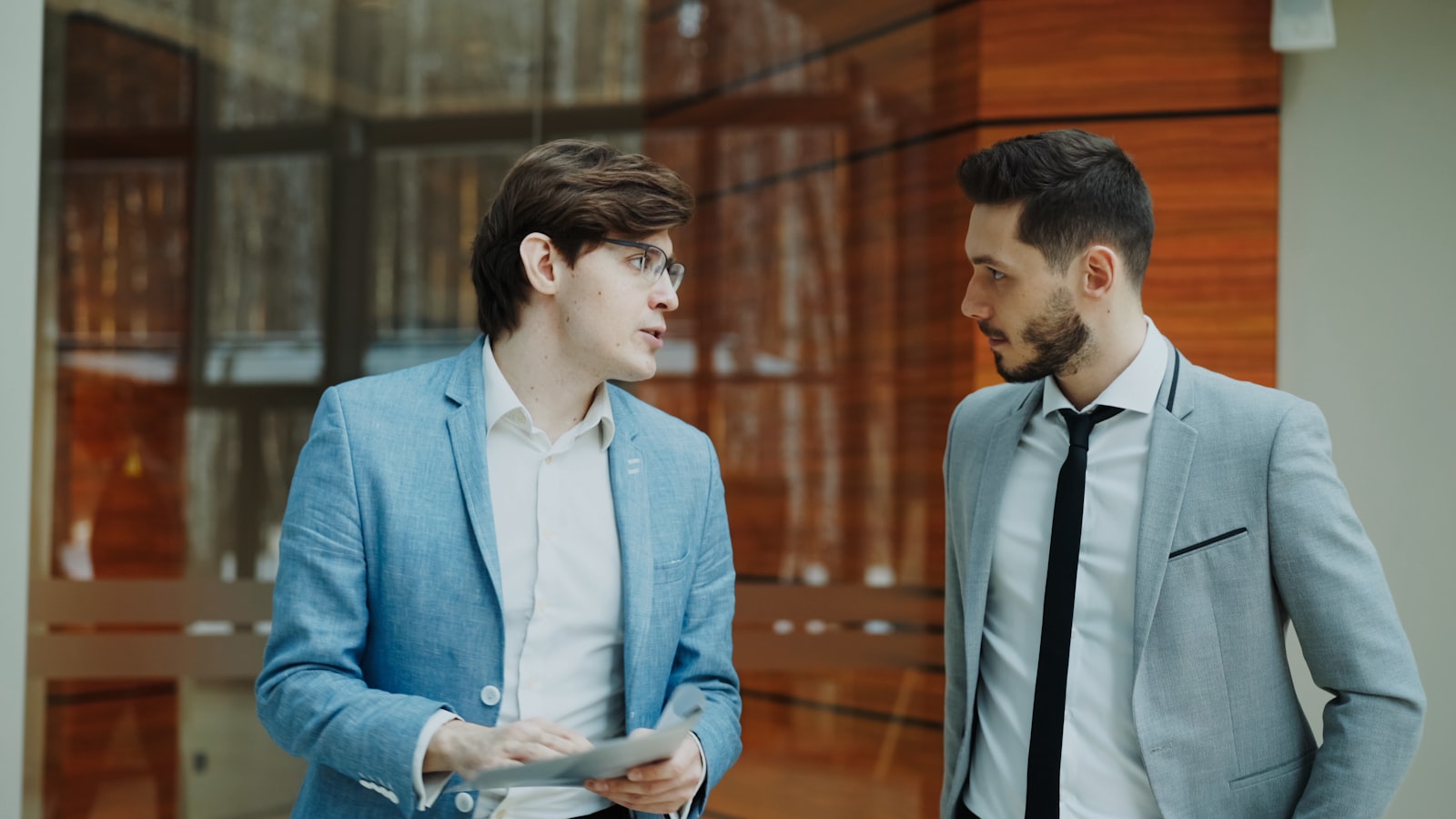 Two insurance professionals in suits reviewing a case together indoors, representing the human oversight layer over AI agents that automate on-premises claims processing