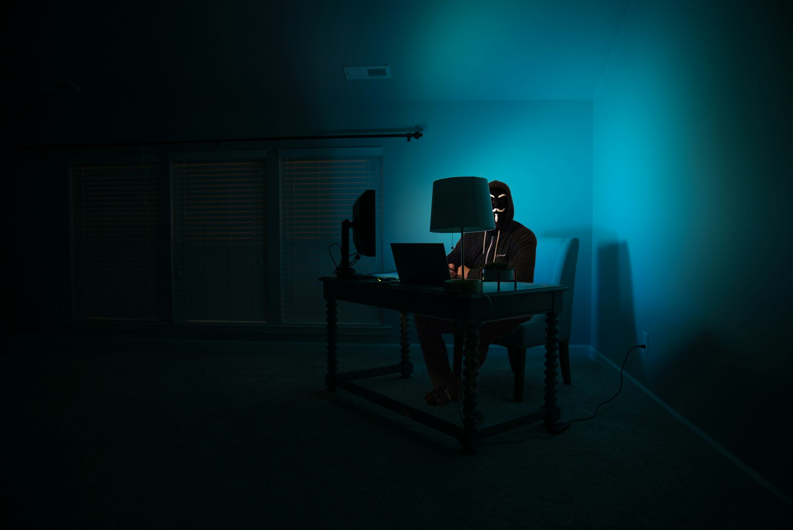 An analyst working at a laptop in a dim, security-focused setting, representing the human investigator supported by governed on-premises AI agents in KYC and AML compliance workflows