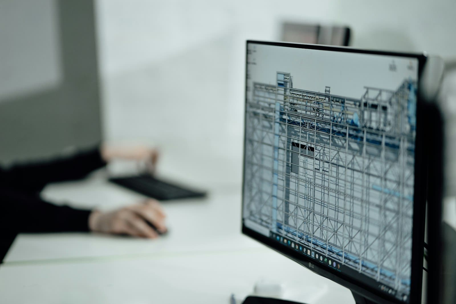 A specialist at a desk reviewing a detailed technical model on a monitor, representing the document-heavy regulatory submission preparation work that on-premises AI agents can support inside a regulated organisation's own security boundary