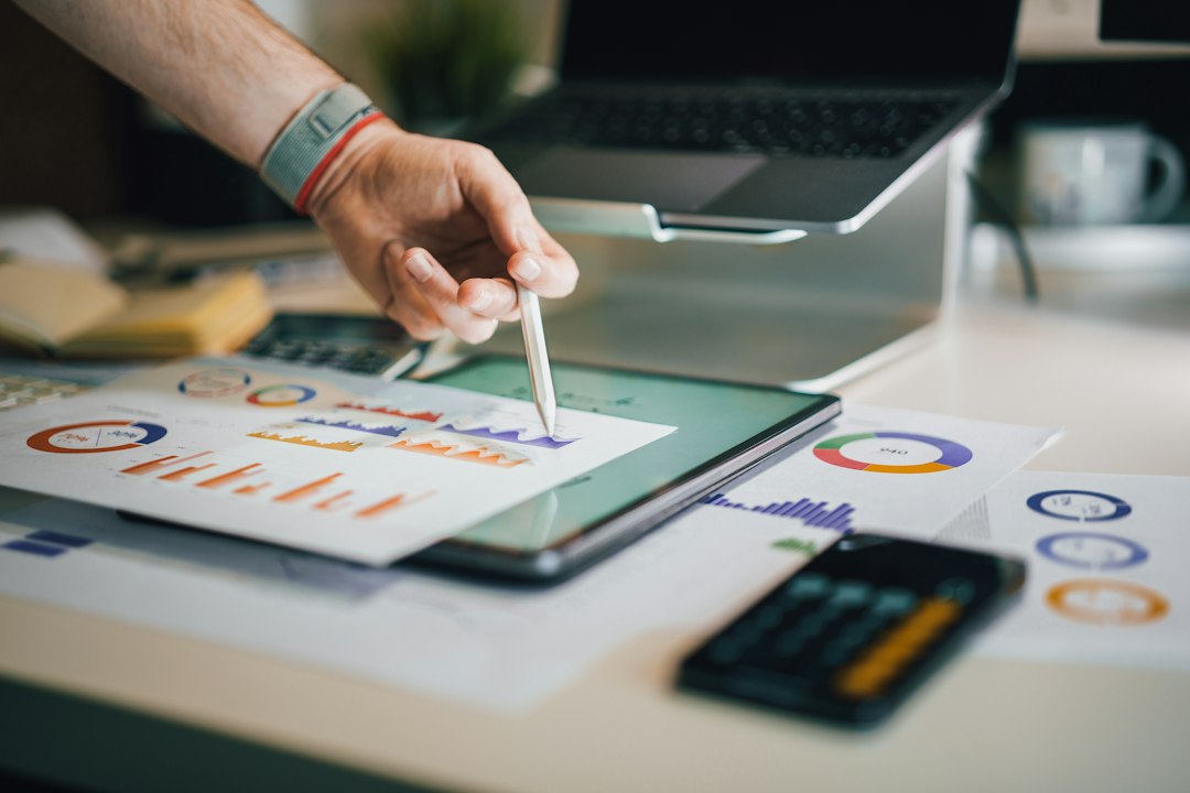 A hand points a stylus at charts on a tablet beside printed bar and donut charts, like a reviewer reading a model's evaluation results