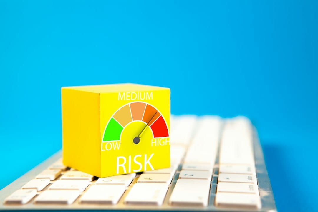 A yellow cube printed with a low, medium and high risk gauge resting on a white computer keyboard, representing likelihood-and-impact scoring in an AI risk assessment