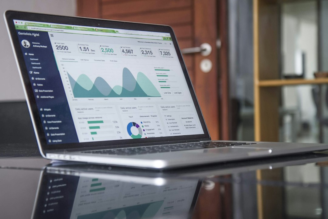 A laptop on a glass table shows a dashboard of figures and area charts, similar to a register that tracks risks and their scores