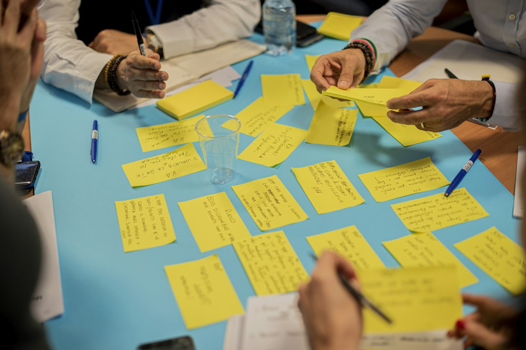 A team writes ideas on yellow sticky notes spread across a blue table during a workshop to collect AI use cases