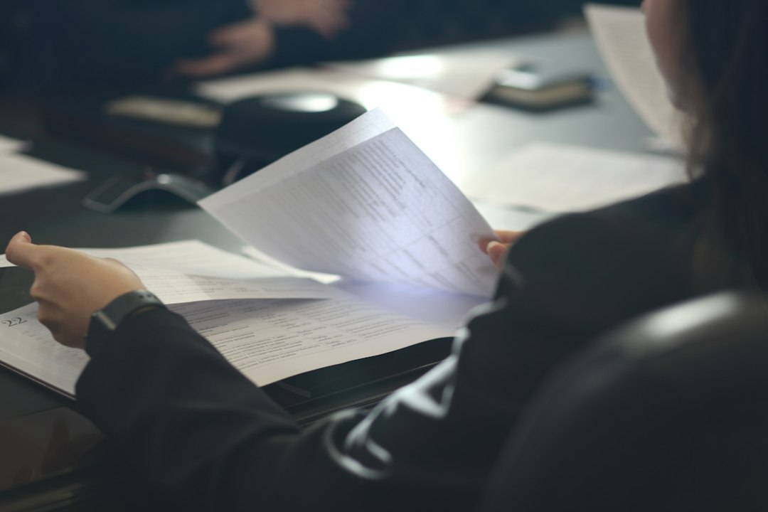 A person at a desk reads a printed document, the kind of paper record that has to be scanned and turned into text