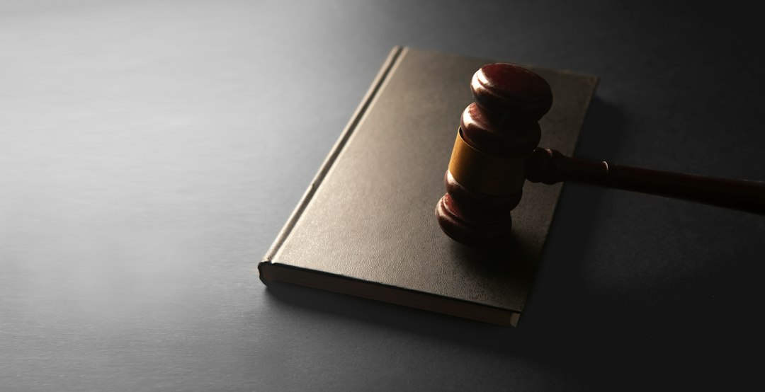 A wooden judge's gavel resting on a closed grey book on a dark table, representing the penalties regulators can impose under the EU AI Act