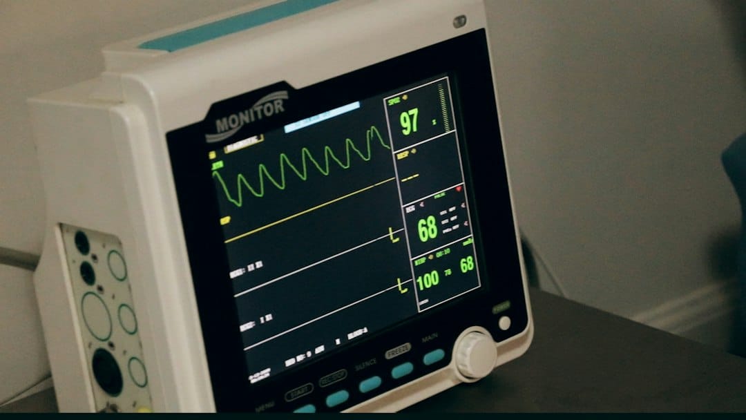 A bedside patient monitor showing vital-sign waveforms and readings on a dark screen, representing medical device software that the EU AI Act can treat as high-risk through the MDR