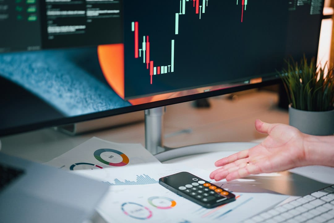 A hand gesturing over printed charts and a calculator on a desk, in front of a large monitor showing a chart, the kind of review where evaluation scores for a language-model release are compared