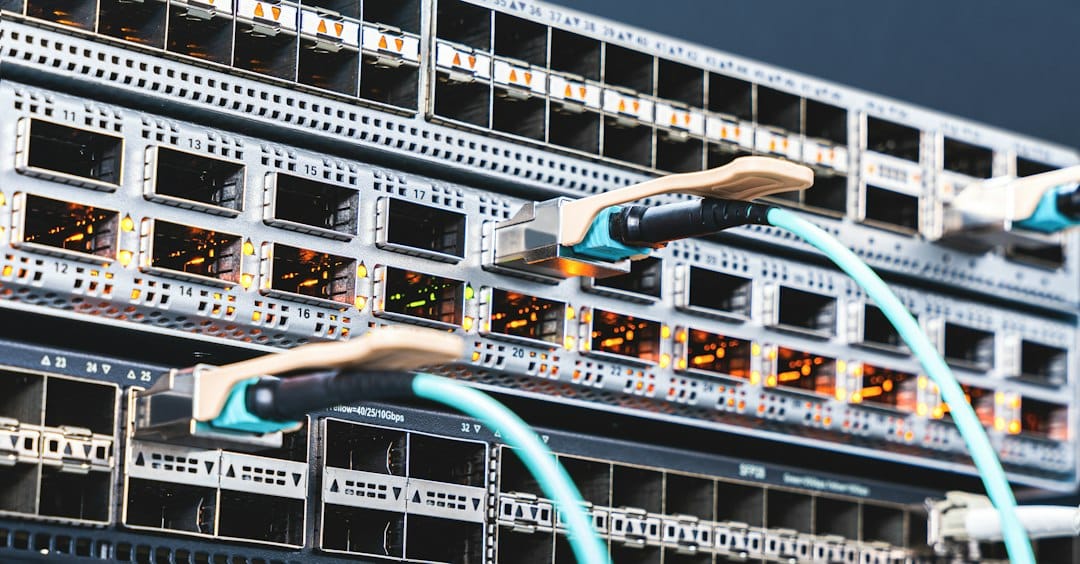 Close-up of a network switch with fibre optic transceivers and cables plugged into its ports, standing for the way Copilot requests can be routed between data centre regions