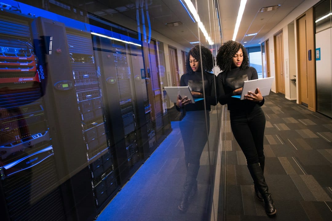 An engineer holding a laptop beside a row of server cabinets in a data centre corridor, representing a company running Mistral models on its own infrastructure