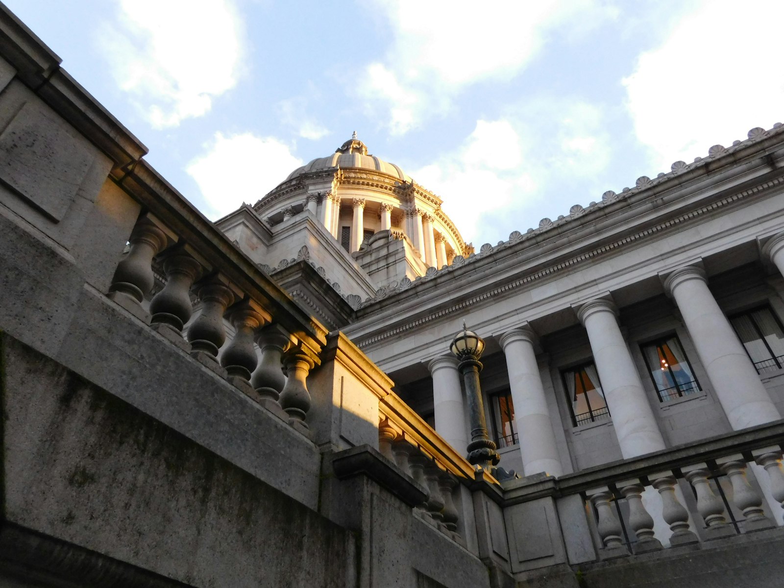 The domed Washington State Capitol in Olympia seen from below, past a stone balustrade, with late afternoon sun on its columns