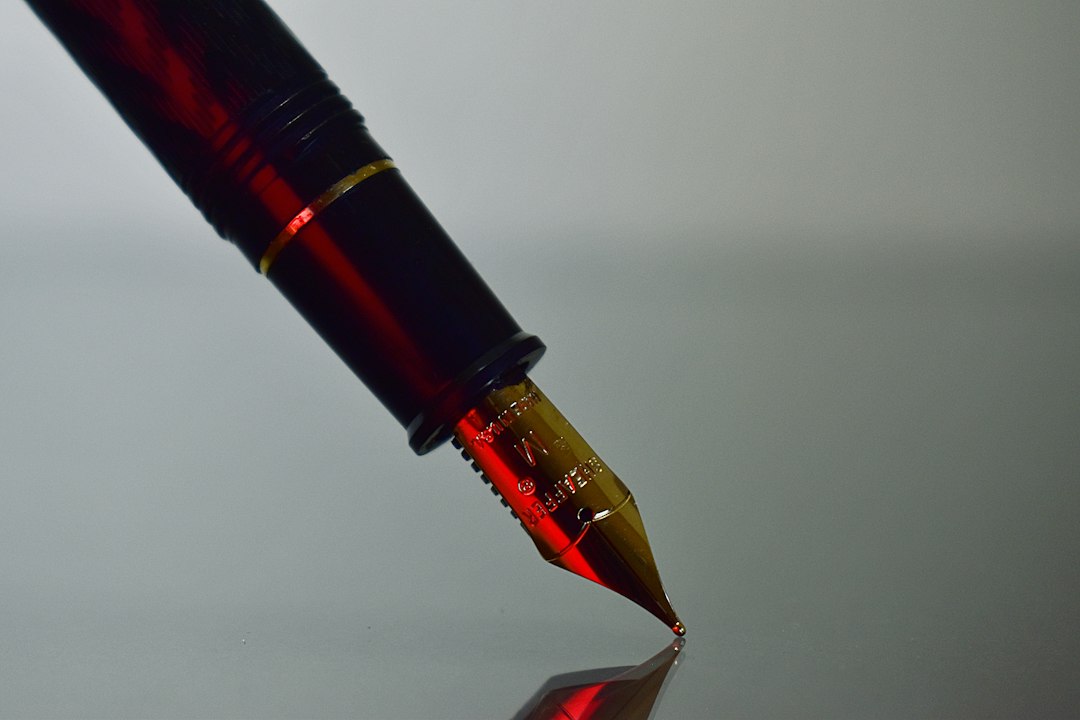 Close-up of a fountain pen nib with red ink touching a grey surface, a stand-in for signing a software licence agreement
