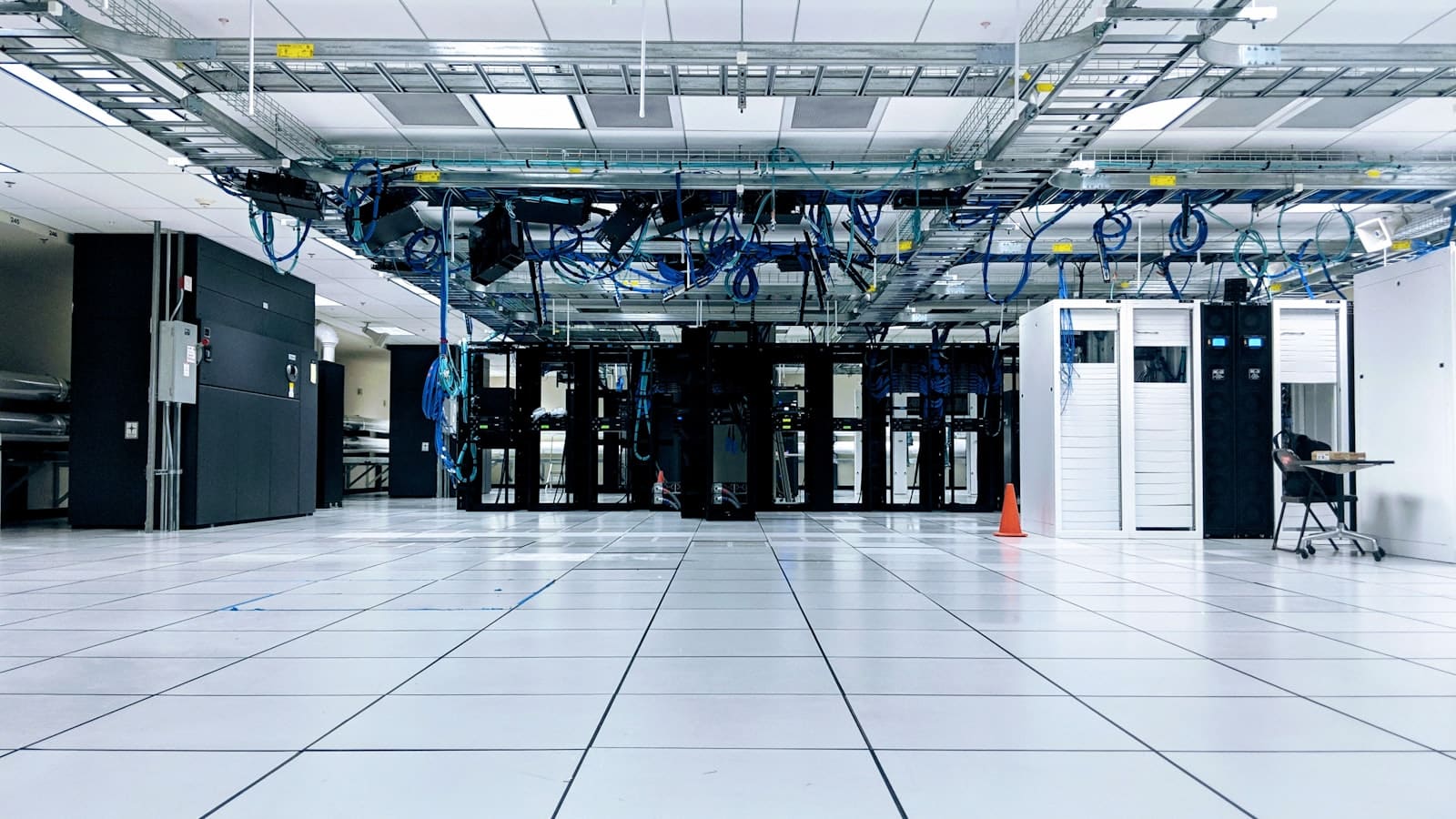 A raised-floor enterprise data centre hall with separated rows of server racks and overhead cabling, representing the distinct development, testing, and production environments of an on-premises AI platform running inside the organisation's own infrastructure