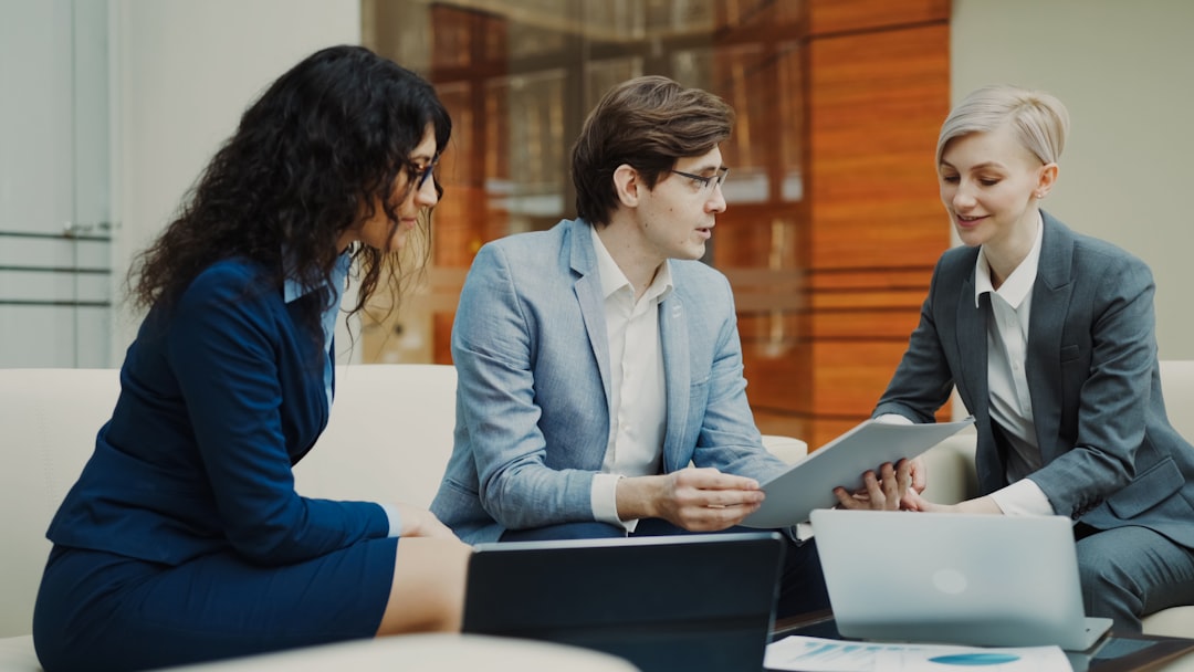 Three business professionals reviewing compliance documents around a conference table, representing executive-level AI governance and board accountability for regulated AI systems